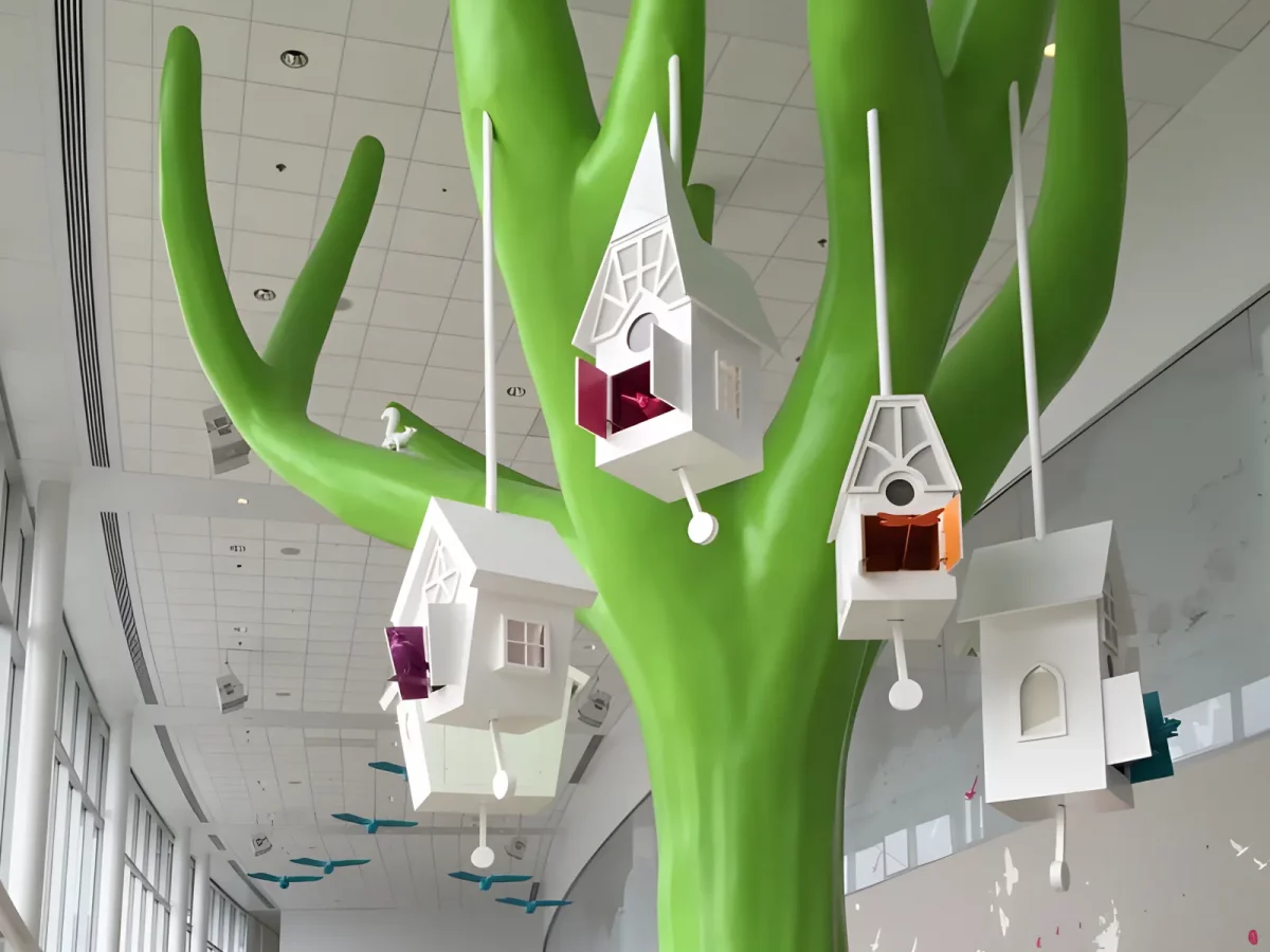 Tree in hospital hallway with hanging birdhouses