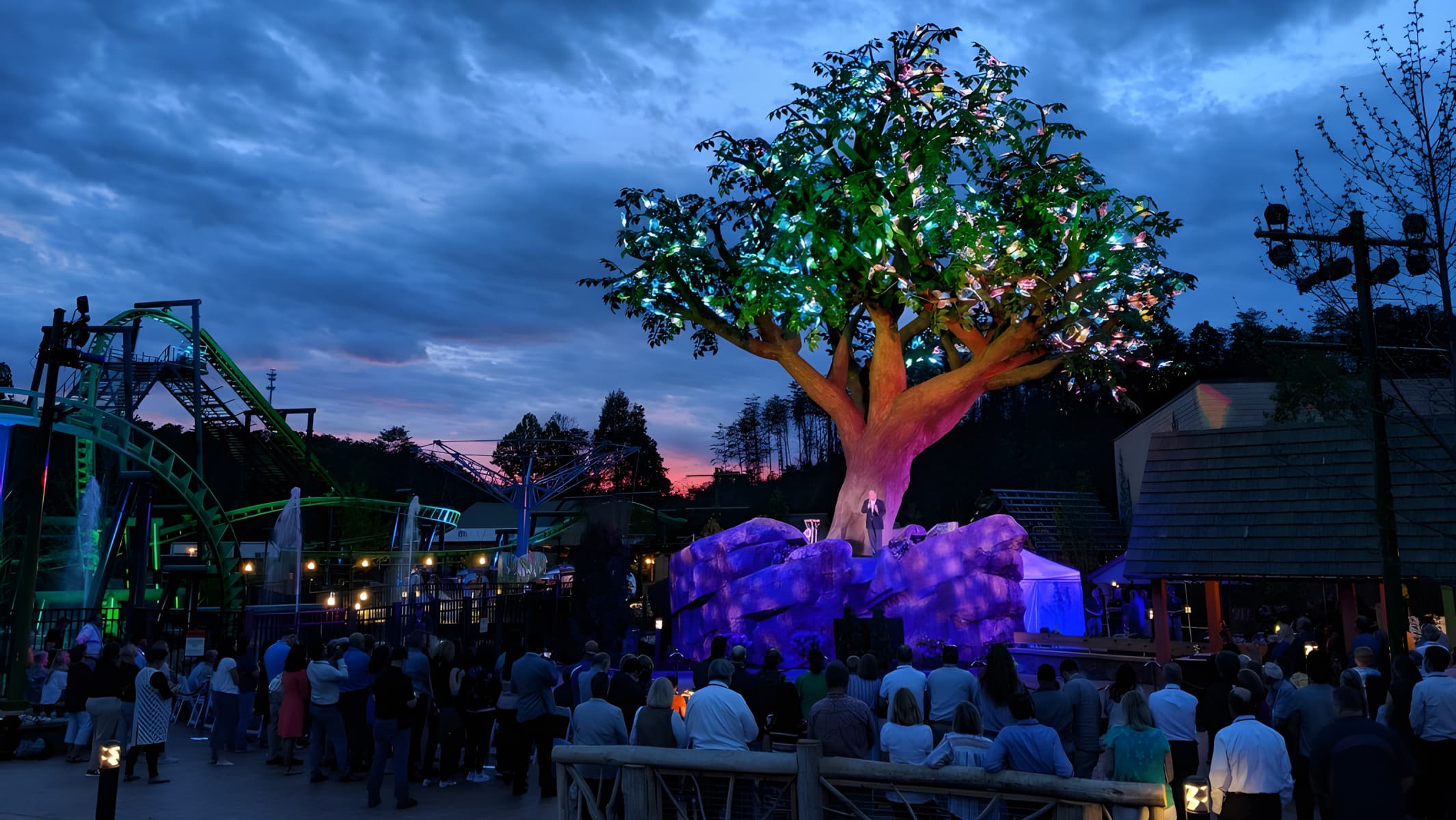 Dollywood tree lit up at sunset with large crowd of people